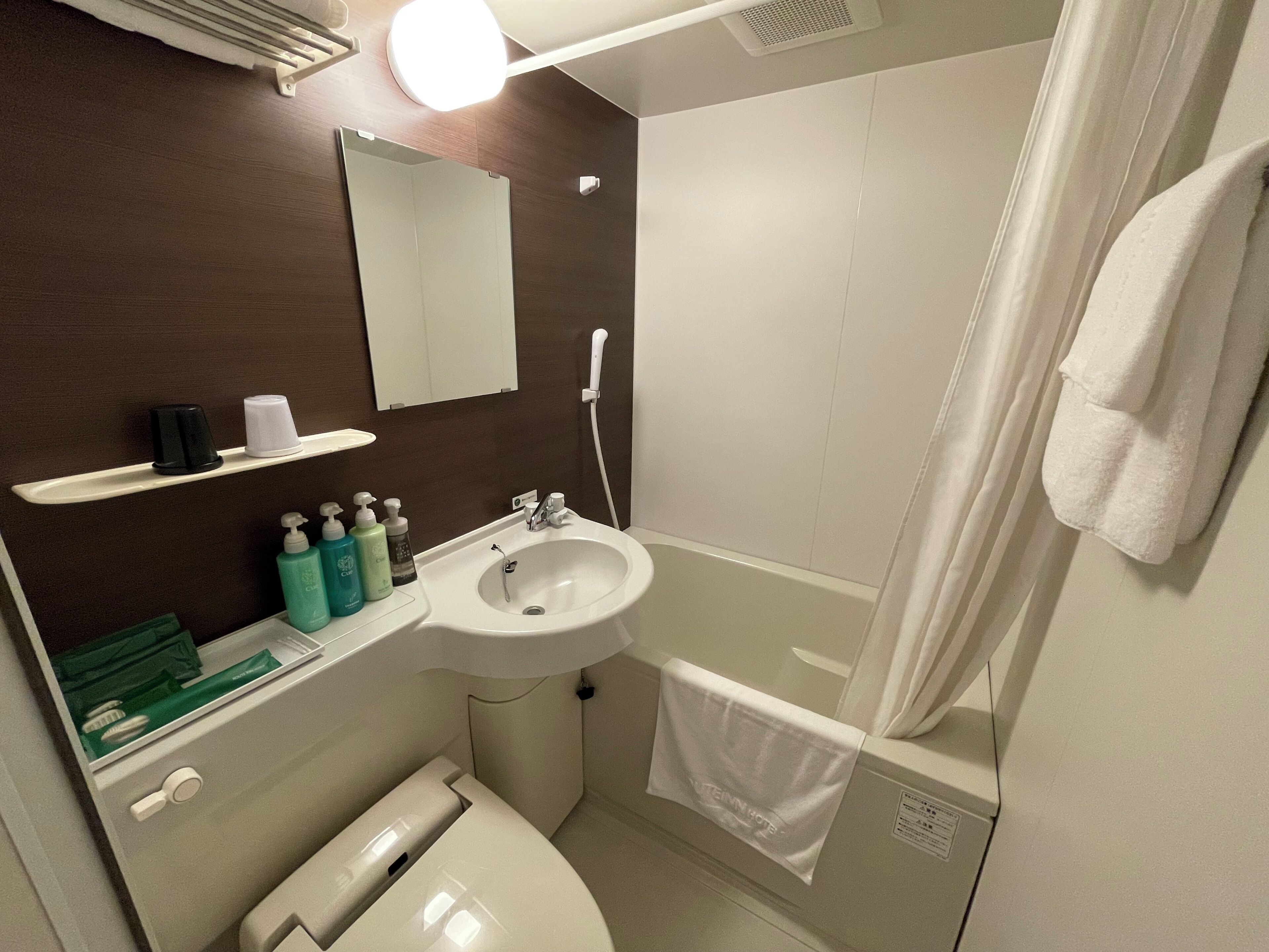 A bathroom with a sink, mirror, shower, and toilet.
