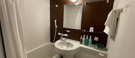 A bathroom with a bathtub, a sink, a toilet, and a mirror.