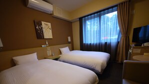 A hotel room with two beds, a TV, a desk, and a window with curtains.