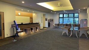 A hotel reception area with a closed sign, a reception desk, and a seating area with wicker chairs and tables.