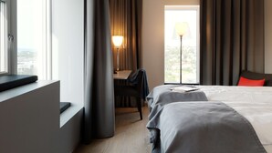 Een hotelkamer met een bed, een bureau, een stoel en een raam met gordijnen.