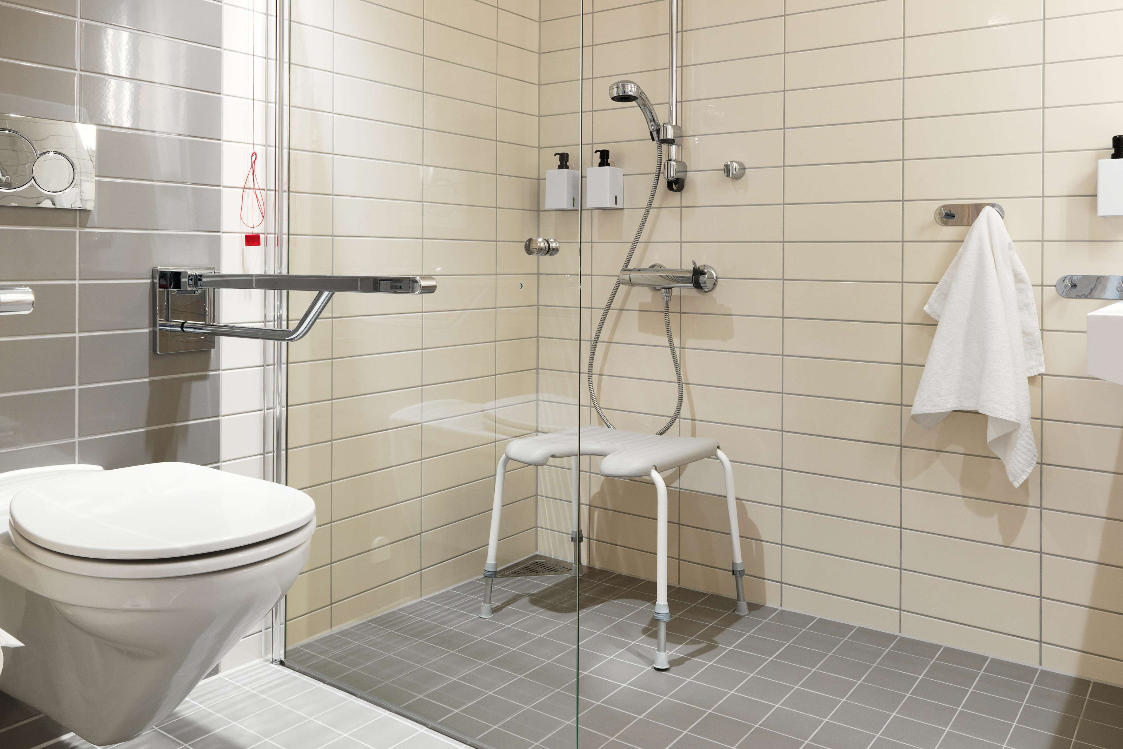 Um banheiro moderno com vaso sanitário, chuveiro com porta de vidro e porta-toalhas.