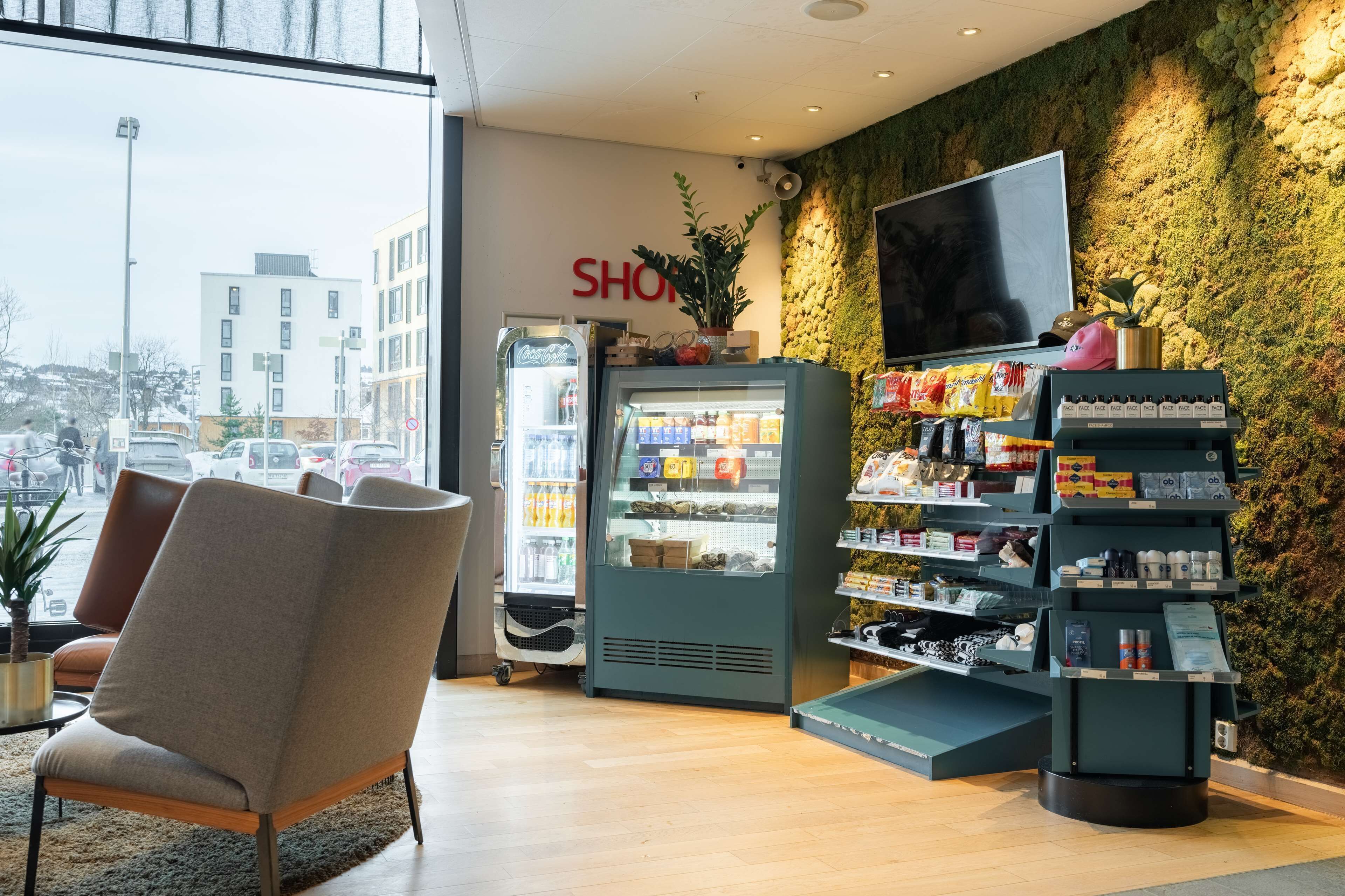 A modern interior with a seating area, a refrigerated display case, and a wall-mounted TV.
