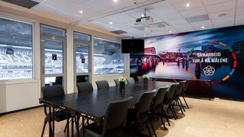 A conference room with a large table, chairs, and a projector screen.