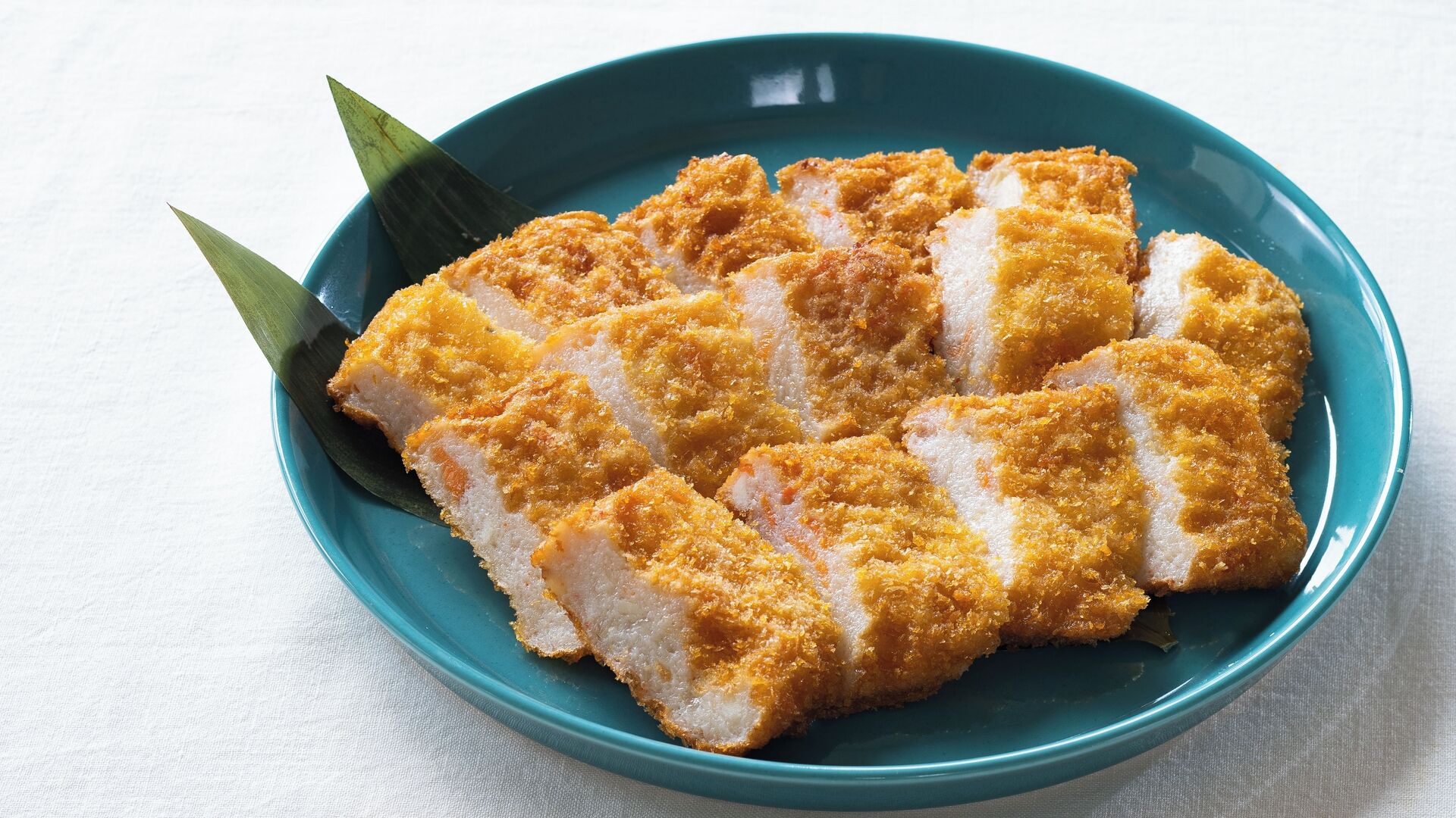 A bowl of breaded and fried food, possibly a type of Japanese dish, on a teal plate.