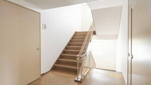 A staircase with a metal railing, a wooden floor, and a door with the number 3 on it. - Vessel Hotel Higashi - Hiroshima (Higashihiroshima)