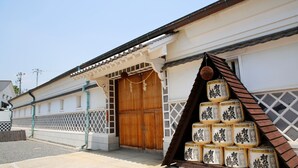 A traditional building with a wooden door and a display of sake barrels outside. - Vessel Hotel Higashi - Hiroshima (Higashihiroshima)