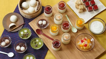 A variety of Asian desserts and snacks arranged on a wooden board and a plate, including steamed buns, jelly desserts, and sweet treats.