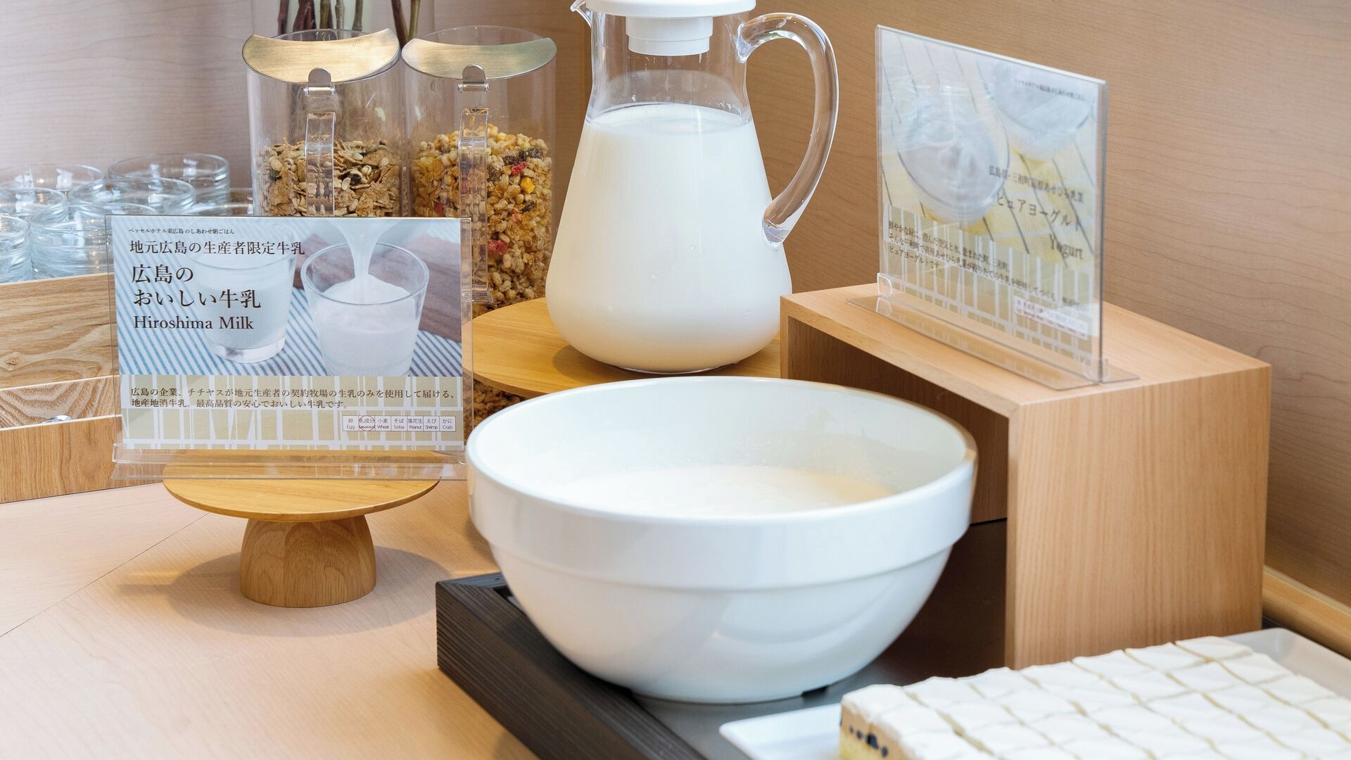 A display of dairy products including a pitcher of milk, a bowl, and a sign with text.