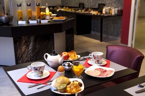 A breakfast setup with various food items, a teapot, and a cup on a table. - Brit Hotel Belfort Centre - Le Boreal (Belfort)