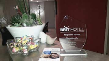 A reception area with a potted plant, a glass trophy, and a brochure on a table.