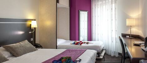 A hotel room with two beds, a desk, and a chair.