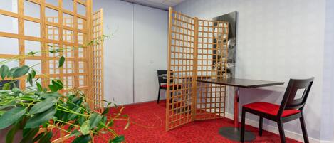 Ein Zimmer mit rotem, gemustertem Teppich, einem Tisch mit Stuhl und einer Holzwand.