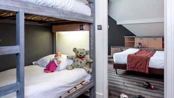 Quarto com beliche, um urso de pelúcia e uma boneca na cama inferior.