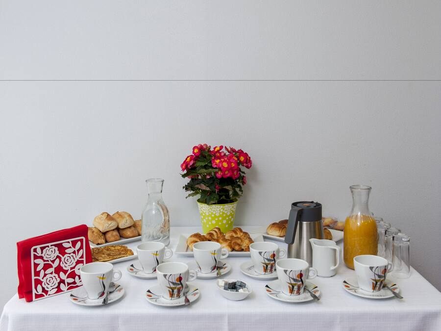 Een ontbijttafel met croissants, gebak, koffiekopjes, een thermoskan en een karaf sinaasappelsap.