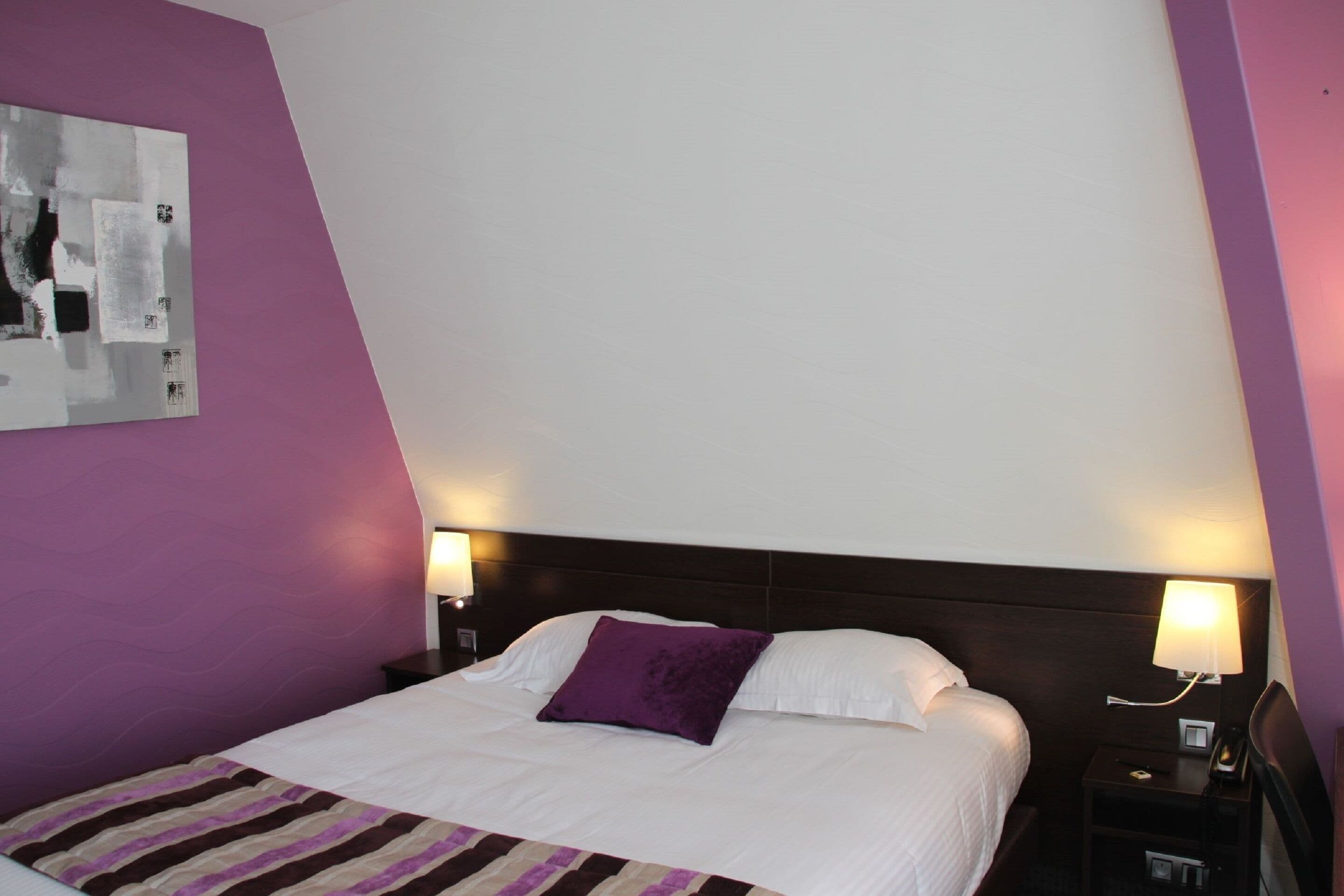 Une chambre d’hôtel comprenant un lit, deux lampes de chevet, une table de chevet et une œuvre d’art accrochée au mur.