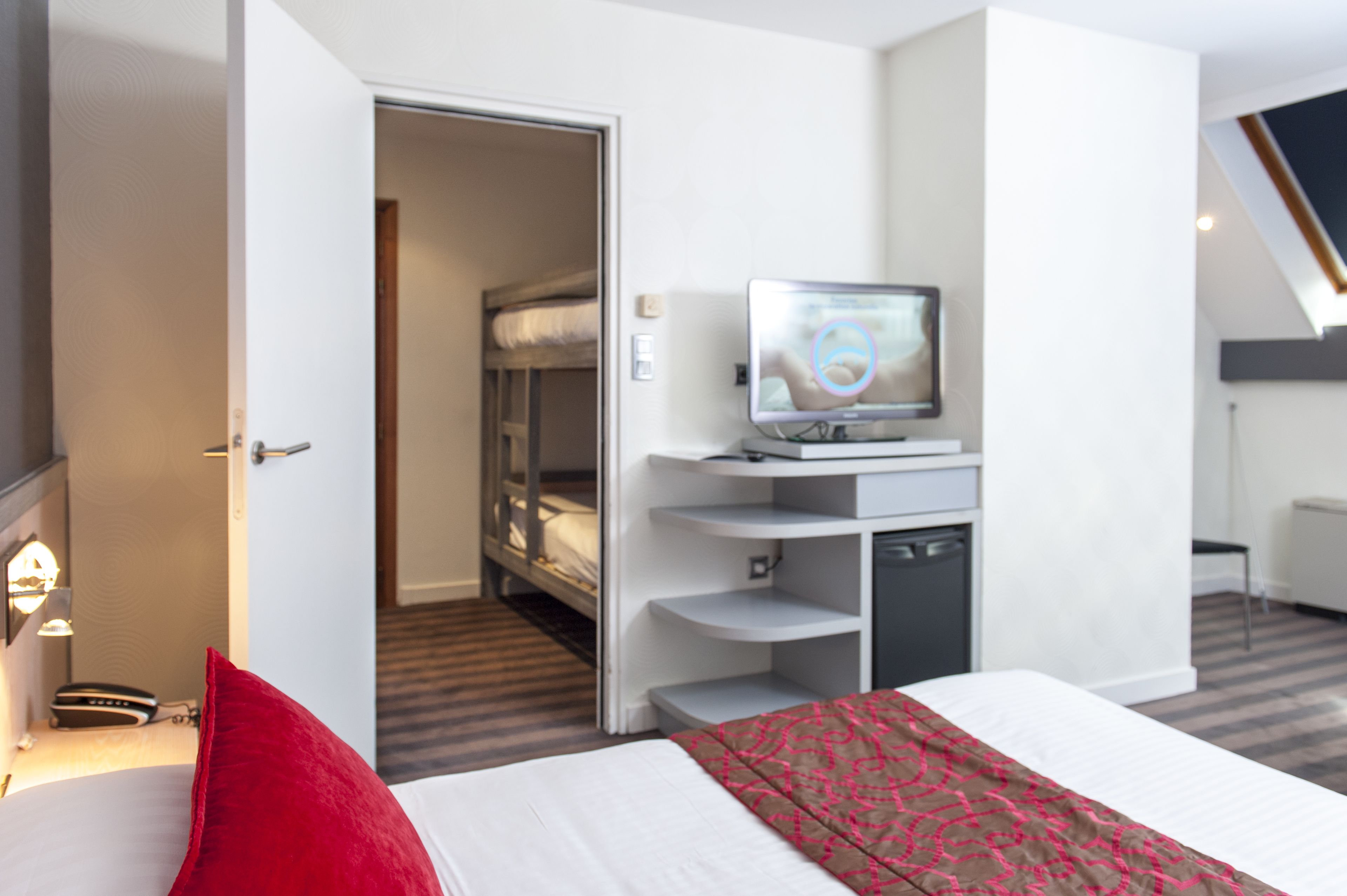 Habitación de hotel con cama, televisión, escritorio con computadora, armario y baño.