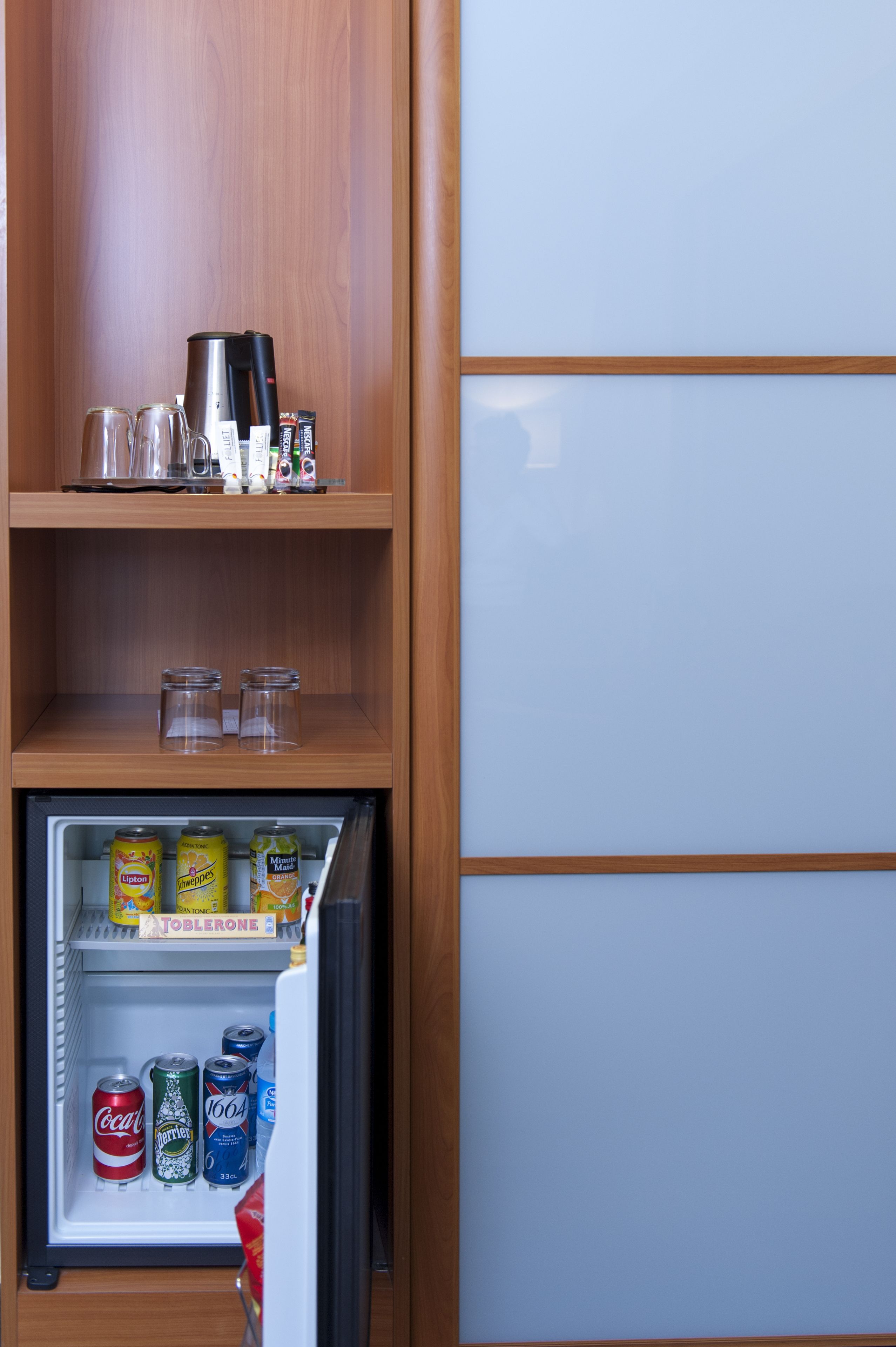 Ein Kühlschrank voller Getränke und eine Kaffeemaschine auf der obersten Ablagefläche.