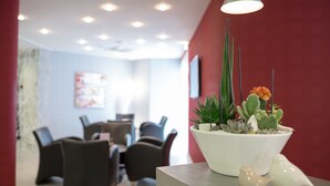 Un interior moderno con una maceta blanca sobre una mesa, que presenta diversas plantas y dos pájaros de cerámica.