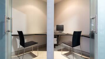 Un espace de bureau moderne avec deux chaises noires, un bureau avec un ordinateur et une cloison en verre.
