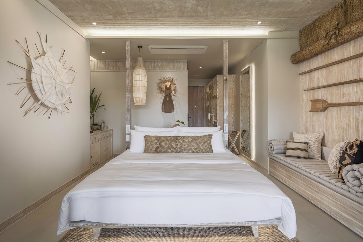 Een moderne slaapkamer met een groot bed, een hanglamp en een wandplank met decoratieve items.