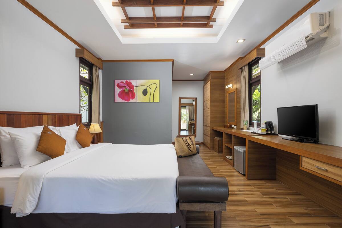 Een moderne hotelkamer met een groot bed, een bureau met een televisie en uitzicht op de omgeving.