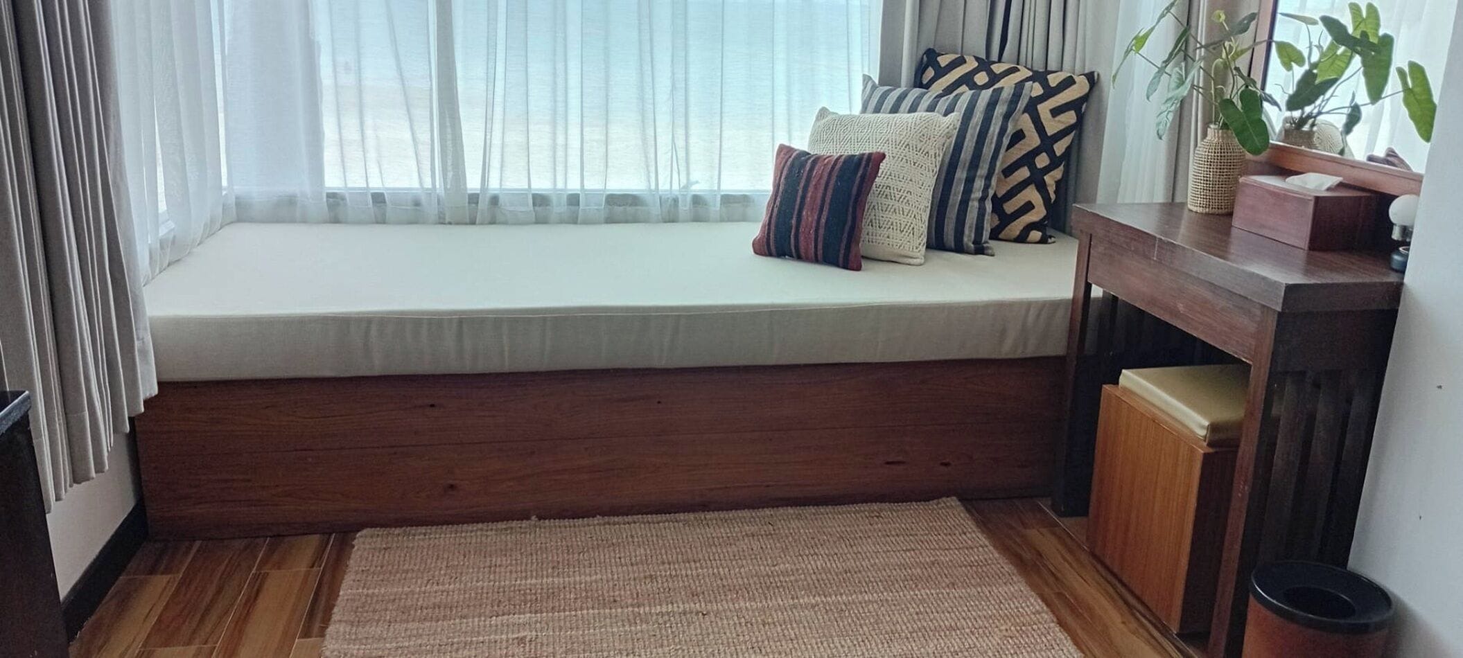 A room with a built-in bench, a small wooden cabinet, and a woven rug.