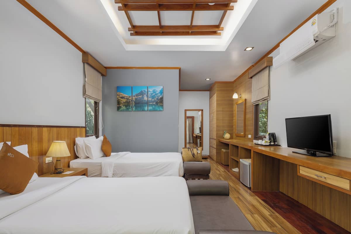 Een hotelkamer met twee bedden, een televisie, een bureau en een groot raam.