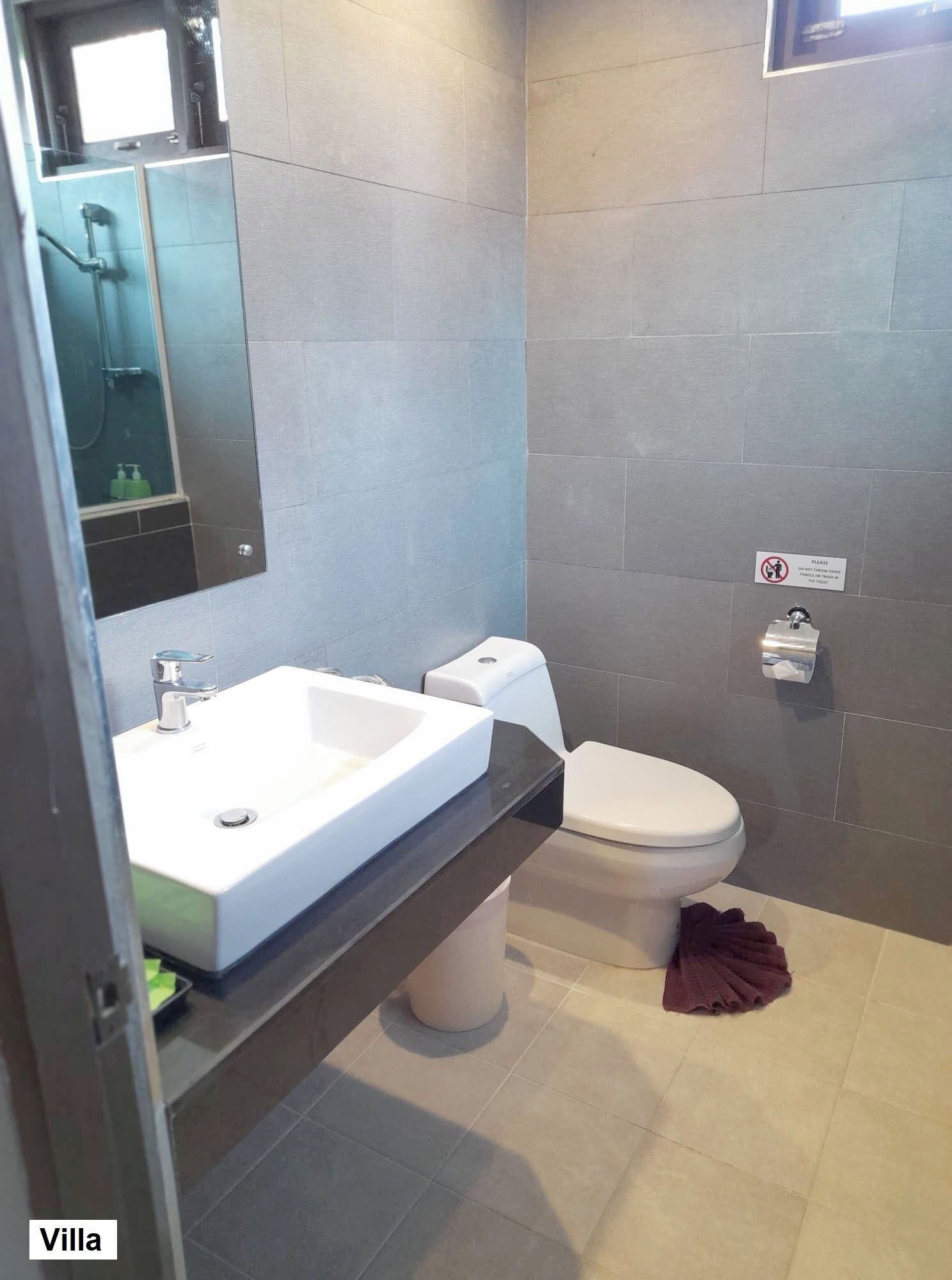 A modern bathroom with a white sink, a toilet, and a mirror.