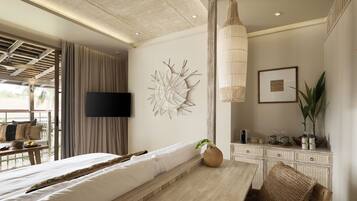 Una habitación de hotel moderna con una cama grande, una zona de comedor, un televisor y un adorno en la pared.
