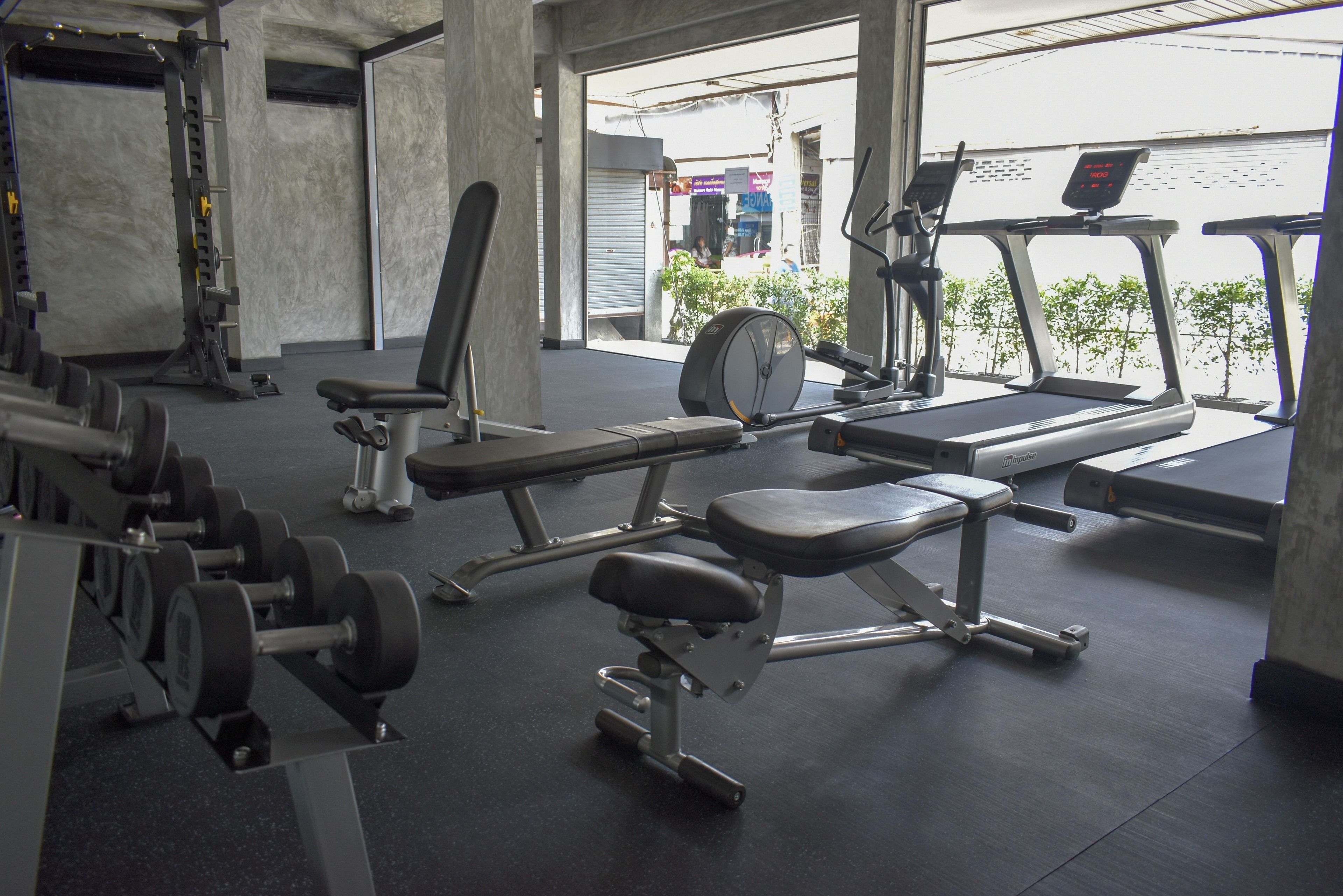 Ein Fitnessstudio mit Gewichte, Laufbändern und einer Bank.