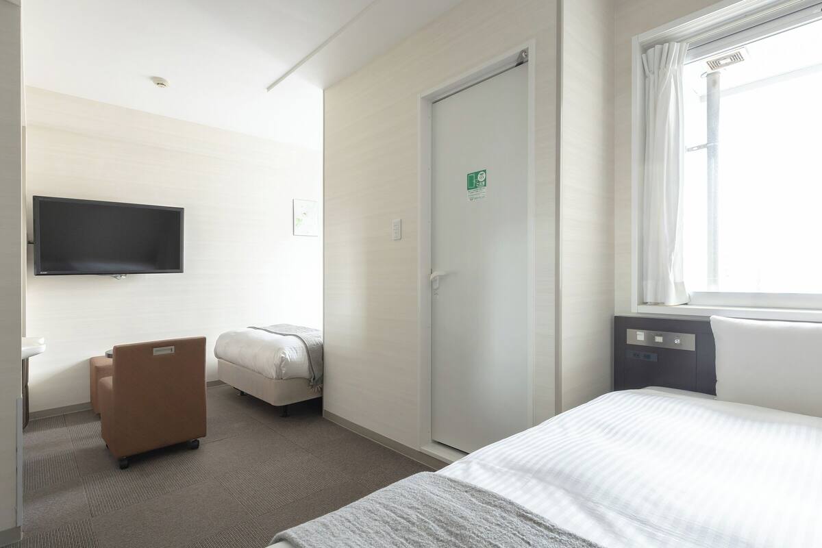 Habitaci ón de hotel con cama, escritorio, silla, televisor, puerta y ventana.