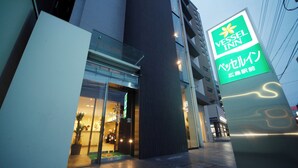 A Vessel Inn hotel entrance with a modern glass facade and a prominent sign. - Vessel Inn Hiroshima Station (Hiroshima)