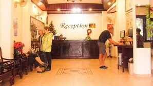 Une salle d’attente avec un plafond en bois, un comptoir d’accueil et quelques personnes présentes.