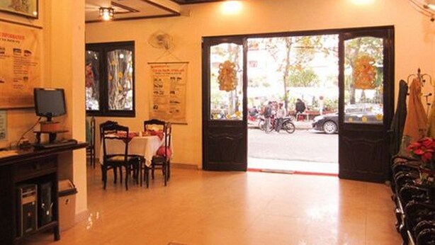 Un intérieur comprenant un comptoir d’accueil, un espace repas avec des chaises et une table, et une vue sur la rue.