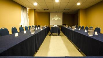 A conference room with a long table, chairs, and a projector screen displaying "HOTEL CONCORDE".