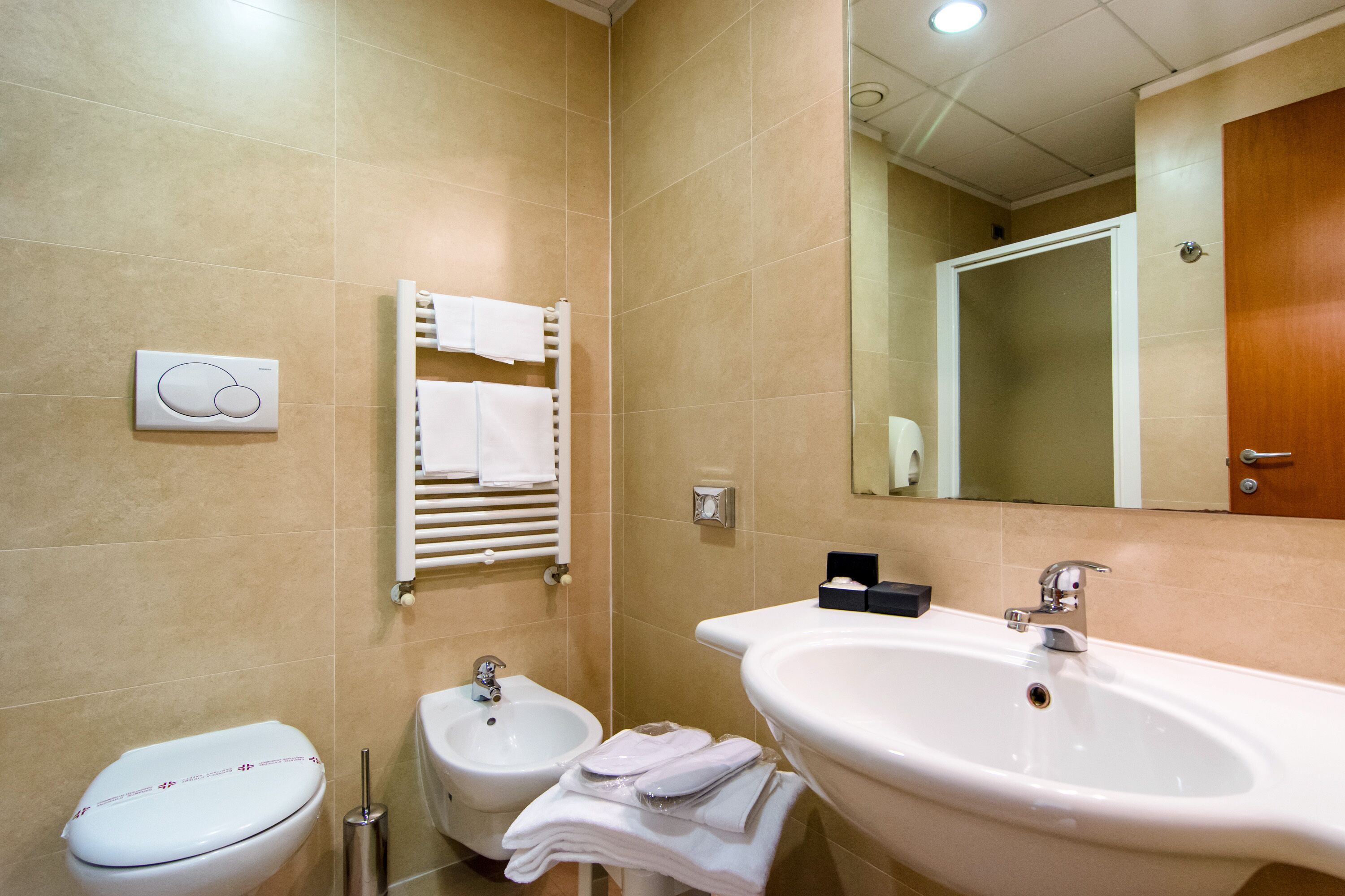 A bathroom with a toilet, bidet, sink, and towel rack.
