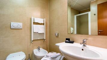 A bathroom with a toilet, bidet, sink, and towel rack.
