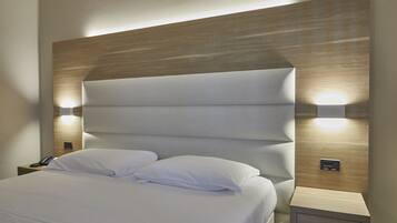 Una habitación de hotel moderna con una cama grande, dos mesitas de noche e iluminación en la pared.