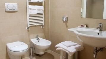 Ein Badezimmer mit Toilette, Bidet, Waschbecken und Handtuchhalter.