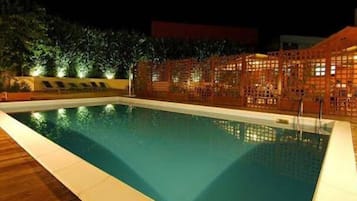 Una piscina con cubierta de madera y una cerca de diseño celosía.