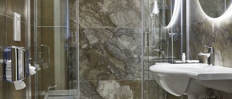 A modern bathroom with a glass-enclosed shower, a freestanding bathtub, and a vanity with a mirror.