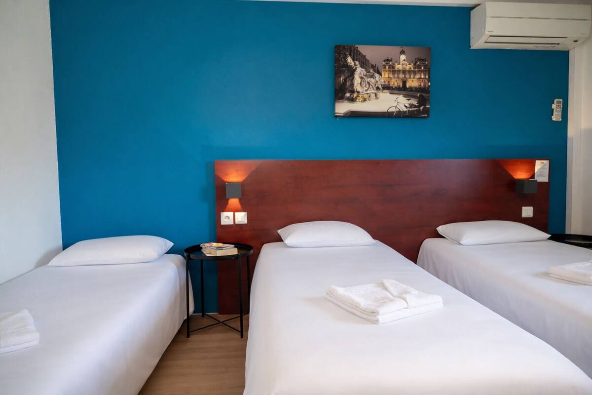 A hotel room with two beds, a nightstand, a wall-mounted picture, and an air conditioning unit.