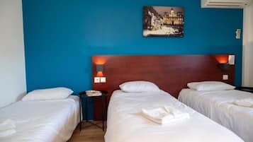 Une chambre d’hôtel avec deux lits, une table de chevet, une lampe et un tableau au mur.
