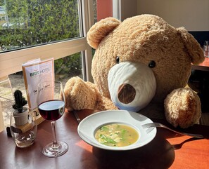 A dining table with a teddy bear, a glass of red wine, a bowl of soup, and a menu sign. -  BRIT HOTEL Essentiel Villefranche-sur-Saône (Ex Balladins) ** (Villefranche-sur-Saône)