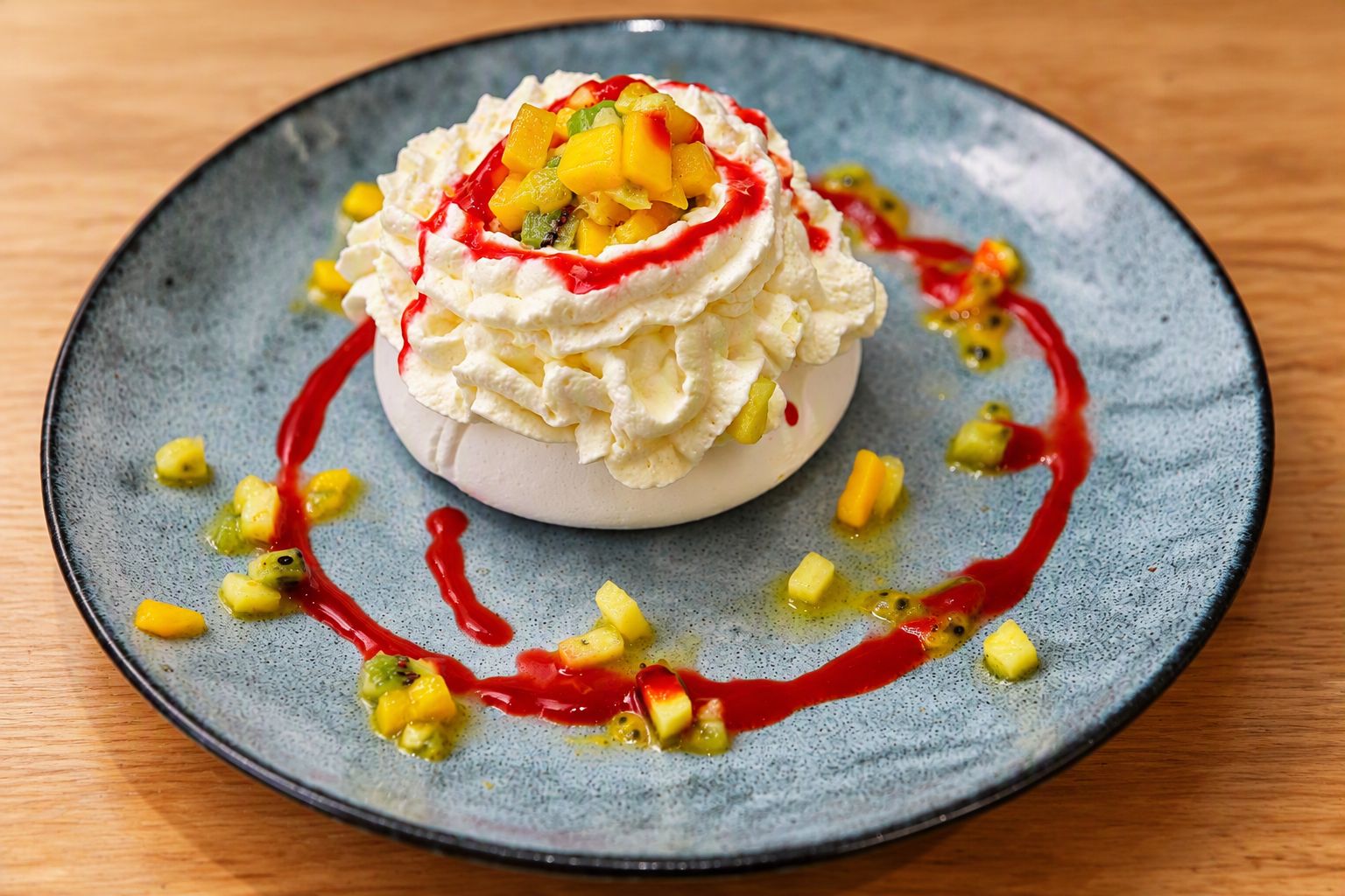A dessert on a plate with fruit pieces and a red sauce.