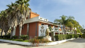 A hotel with a prominent lion statue, palm trees, and a clear blue sky. - Prince Franklyn Hotel (Castellabate)