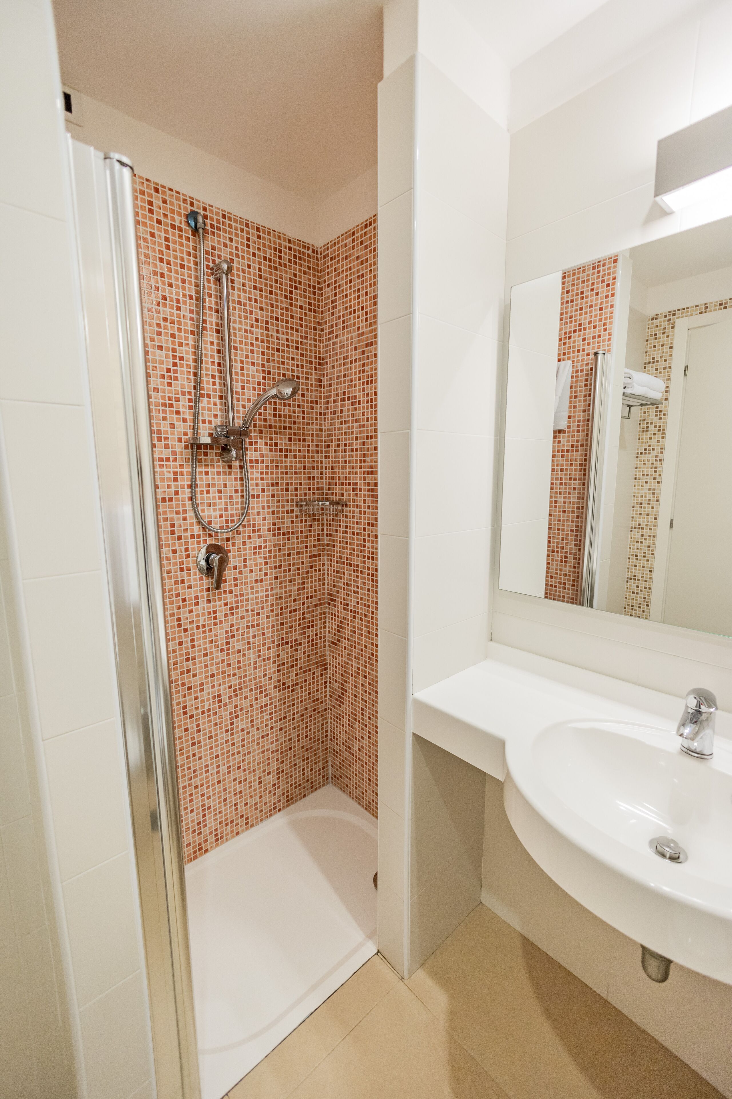 Ein Badezimmer mit Dusche, Waschbecken und Spiegel.
