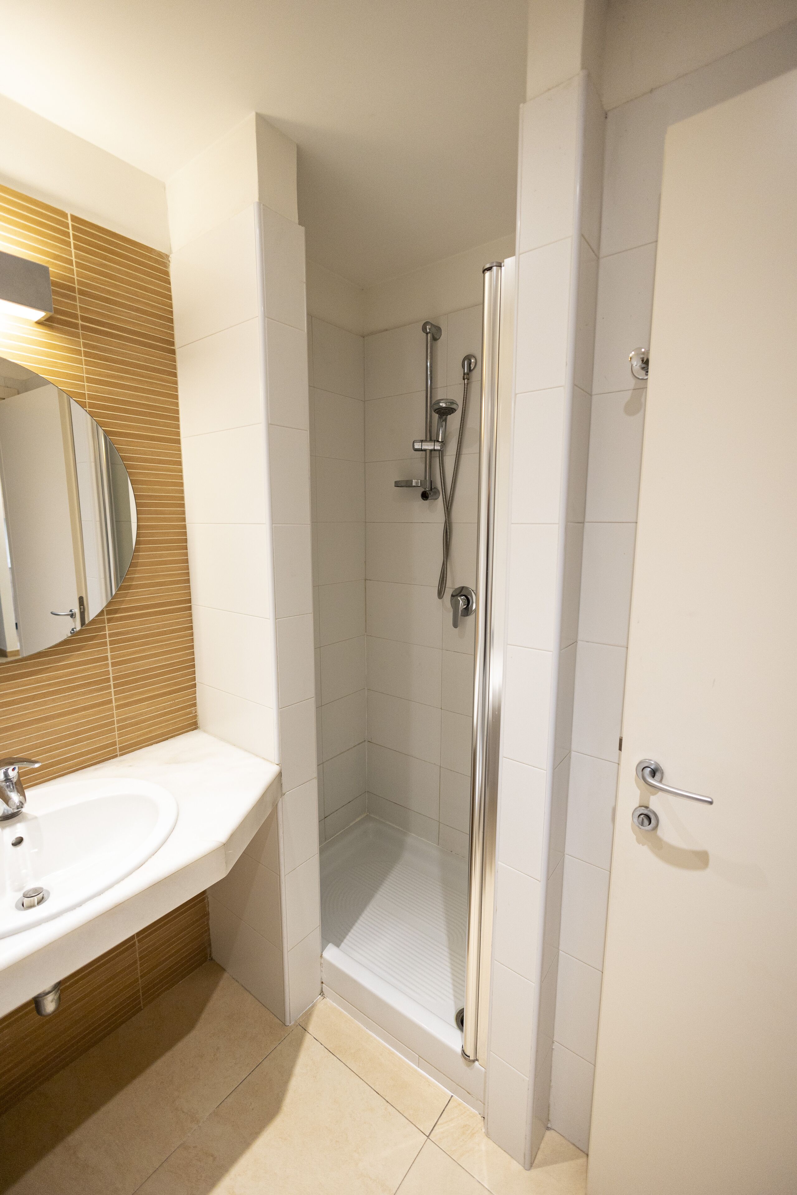 Ein modernes Badezimmer mit einem weißen Waschbecken, einem Spiegel und einer Duschkabine.