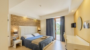 A modern hotel room with a large bed, bedside table, lamp, and a desk with a chair. - Prince Franklyn Hotel (Castellabate)